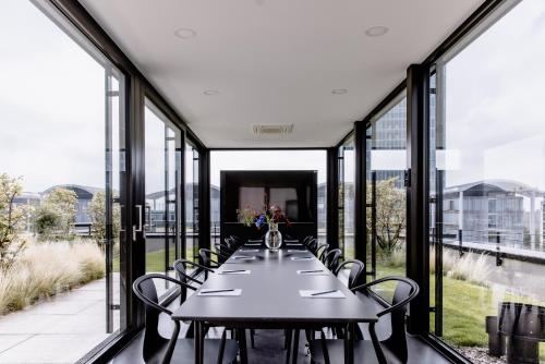 a long table with chairs on a room with windows at THE FLAG München M. in Munich