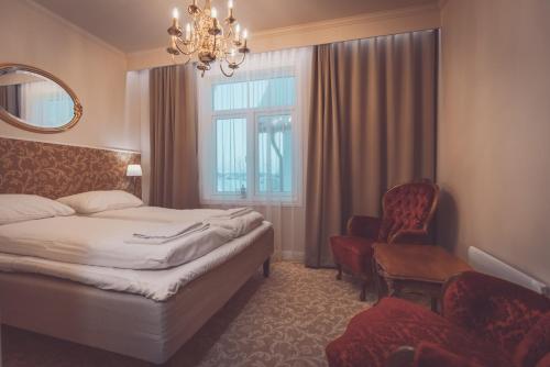 a bedroom with a bed and a chair and a chandelier at Villa Havblikk Tromsø in Tromsø