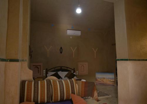a bedroom with a bed in a room with a wall at Casa Laman in Merzouga