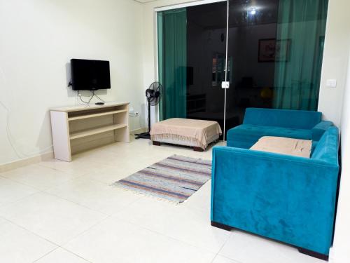 a living room with a blue couch and a tv at HOSTEL FAMÍLIA CASTOR in Itanhaém