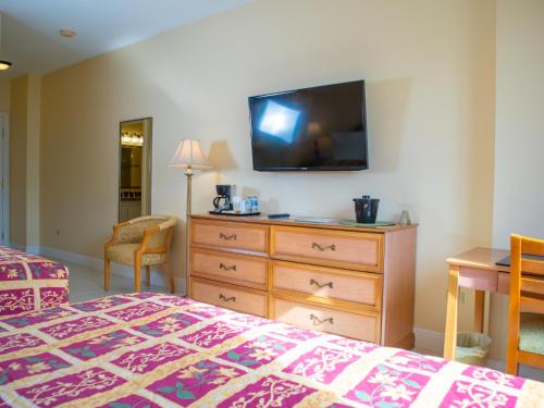 a bedroom with a bed and a dresser with a tv on the wall at Princess Vegas Hotel & Casino in Corozal
