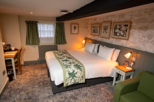 Habitación de hotel con cama grande y escritorio. en Rockingham Arms By Greene King Inns, en Wentworth
