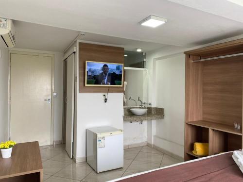 a bathroom with a sink and a tv on the wall at Hotel do Reinildo II in Cachoeira Paulista