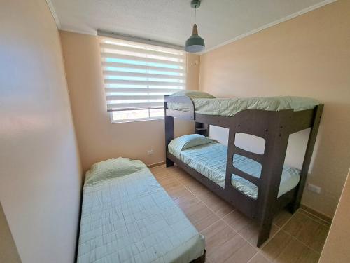 two bunk beds in a room with a window at Departamento completo sector aeropuerto La Serena in La Serena