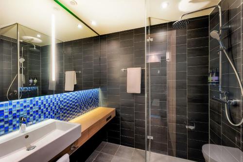 ein Badezimmer mit einem Waschbecken und einer Dusche mit blauen Fliesen in der Unterkunft Premier Inn Heilbronn City Centre in Heilbronn