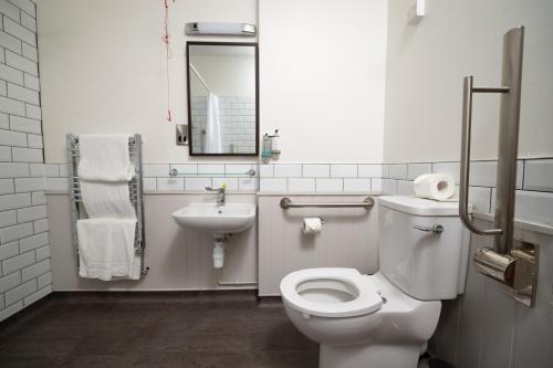 a bathroom with a white toilet and a sink at Rockingham Arms By Greene King Inns in Wentworth