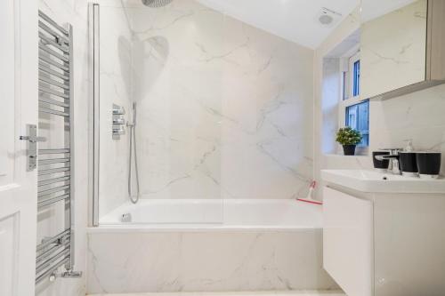 a white bathroom with a tub and a sink at Classy House in Maida Vale - Private Garden in London