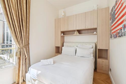 a small bedroom with a white bed and a window at Le Luxe à la Française in Paris