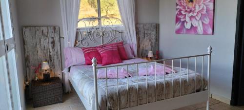 Un dormitorio con una cama con almohadas rosas y una ventana en Casa Ceratonia, en Álora