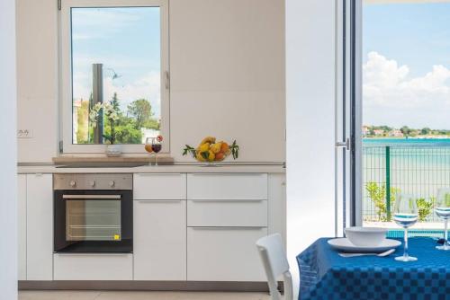a white kitchen with a table and a window at Villa Miri Rosemary in Privlaka