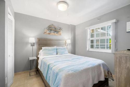 1 dormitorio con 1 cama con edredón azul y ventana en Tropical Getaway w/Private Beach 1 BD Condo, en Tavernier