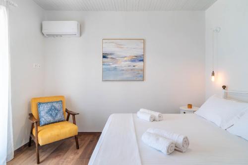 a white bedroom with a yellow chair and a bed at Green Mountain Seaview Suite in Achílleion