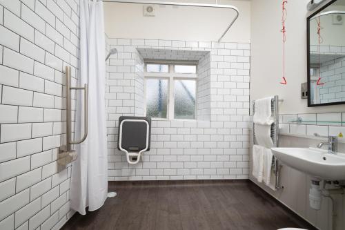 La salle de bains blanche est pourvue d'un lavabo et d'une fenêtre. dans l'établissement Rockingham Arms By Greene King Inns, à Wentworth