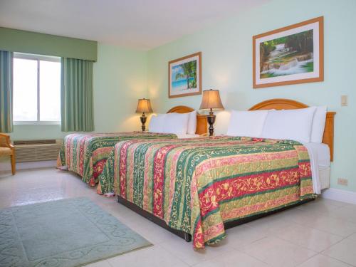 two beds in a hotel room with two lamps at Princess Vegas Hotel & Casino in Corozal