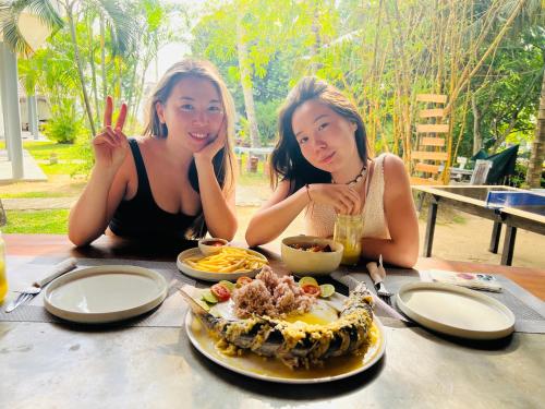 dos mujeres sentadas en una mesa con un plato de comida en PineApple Surf en Ahangama