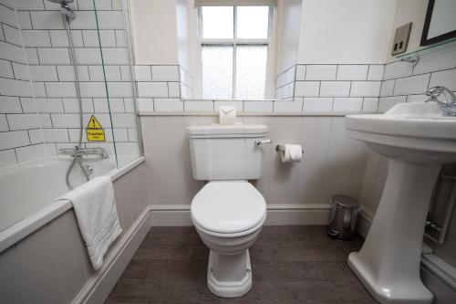 a white bathroom with a toilet and a sink at Rockingham Arms By Greene King Inns in Wentworth