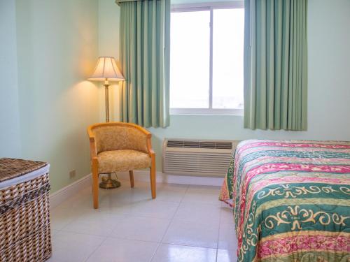 a bedroom with a bed and a chair and a window at Princess Vegas Hotel & Casino in Corozal