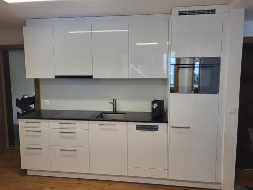 a kitchen with white cabinets and a sink at Jolimont Apartments in Zermatt