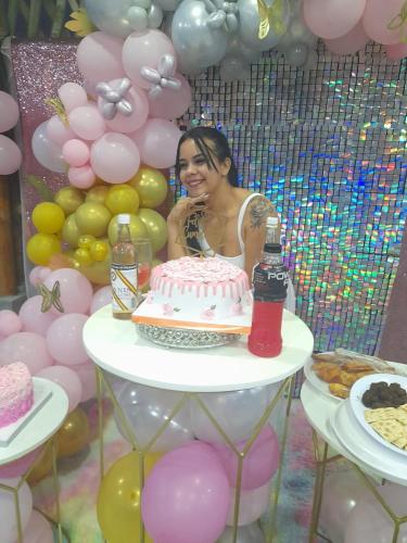 una mujer de pie detrás de un pastel en una mesa con globos en FAMILIA REINOSO en Tonsupa