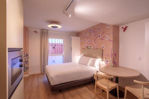 a hotel room with a bed and a table and a bed and a kitchen at Apartamentos Valladolid Centro in Valladolid