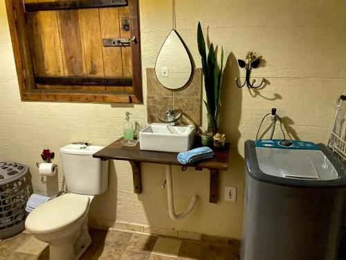 een badkamer met een wastafel, een toilet en een spiegel bij Recanto da Represa Carrancas in Carrancas