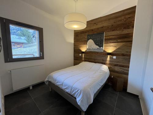 Cette chambre dispose d'un lit avec un mur en bois. dans l'établissement Châtel: Appartement neuf 4 pers, terrasse, parking, local à skis, wifi, ménage inclus - FR-1-198-261, à Châtel
