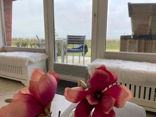 um quarto com uma janela com flores cor-de-rosa e uma cadeira em Haus Kampbarg Suite 2-Meer-Blick em Kampen