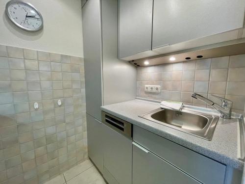uma cozinha com um lavatório e um relógio na parede em Haus Kampbarg Suite 2-Meer-Blick em Kampen