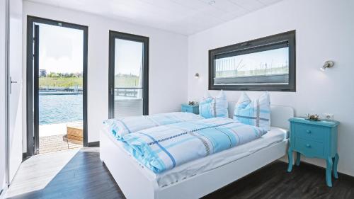 a white bedroom with a bed and a window at Geiseltalsee Hausboot - Floating House - Hausboot Junior in Braunsbedra