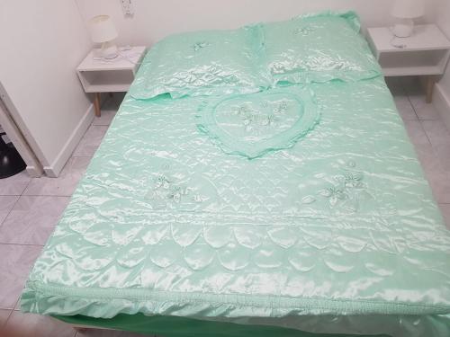 uma cama com um cobertor verde com um coração em MER ET SOLEIL em Port-Louis