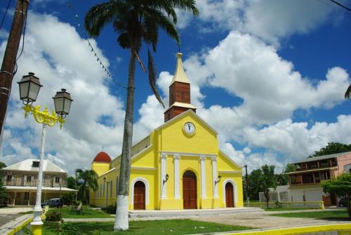 uma igreja amarela com uma torre de relógio numa rua em MER ET SOLEIL em Port-Louis