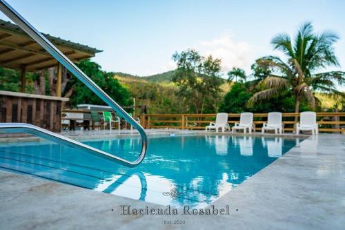 una piscina con sillas blancas y un tobogán en Hacienda Rosabel, en Ponce