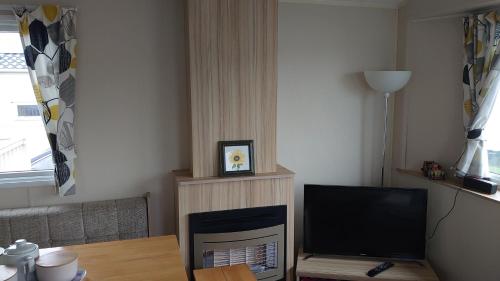 a living room with a television and a table at Your Holidays in Scotland. in Eyemouth