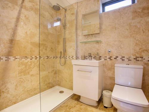 a bathroom with a toilet and a glass shower at Beautiful Seaside Holiday Home in West Bay