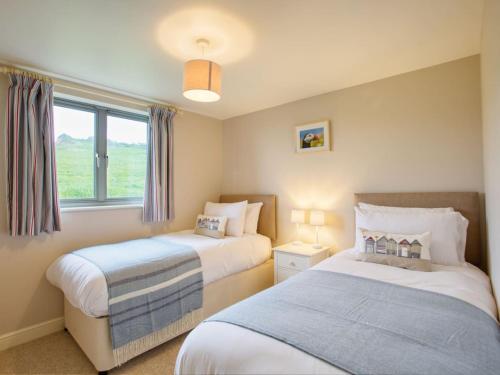 a bedroom with two beds and a window at Beautiful Seaside Holiday Home in West Bay