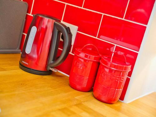 a group of four red cups next to a coffee maker at Beautiful Seaside Holiday Home in West Bay