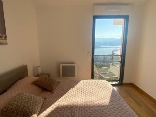 - une chambre avec un lit et une grande fenêtre dans l'établissement A Toretta, magnifique T2 4 pers avec vue mer panoramique, à Ajaccio