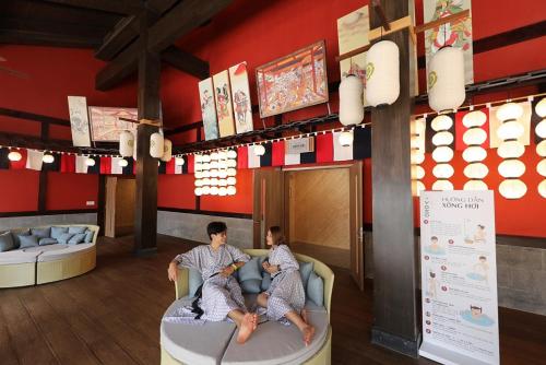 dos personas sentadas en un sofá en una habitación en Vé tắm Yoko Onsen Quang Hanh - khung giờ sáng, en Cẩm Phả