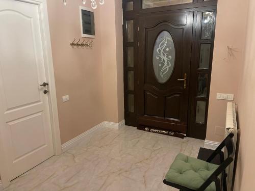 a hallway with a wooden door and a chair and a door at ROOM IN A PRIVATE HOUSE - 5 min from THERME and AIRPORT in Corbeanca