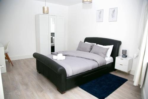 a bedroom with a black bed with a blue rug at Peace Home in Watford