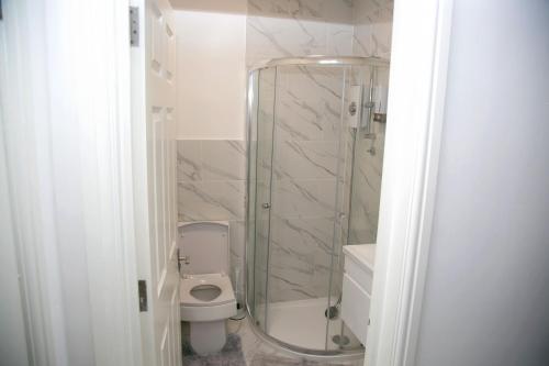 a bathroom with a toilet and a glass shower at Peace Home in Watford