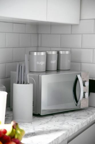 a microwave sitting on a counter with utensils at Peace Home in Watford
