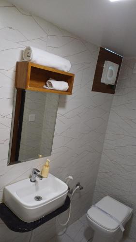 Un baño con lavabo, inodoro y espejo. en Hotel The Grand Jashi Residency, en Pātan