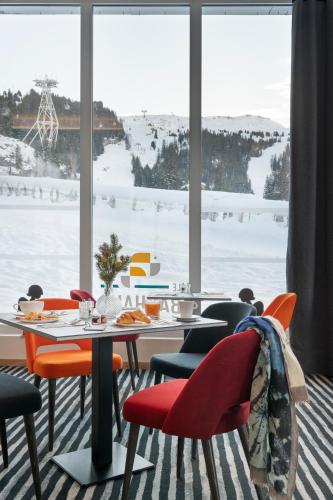 a dining room with a table and chairs in front of a window at MGM Hôtels & Résidences - Hôtel Alhéna in Flaine