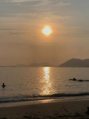 a person swimming in the ocean at sunset at Casa com Praia no quintal in Angra dos Reis