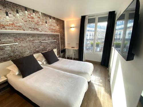 パリにあるベストウエスタン ホテル ル モンパルナスのレンガの壁、ベッド2台が備わるベッドルーム1室が備わります。