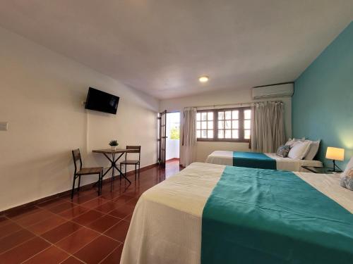 a hotel room with two beds and a table and chairs at Calypso Beach Hotel by The Urbn House Santo Domingo Airport in Boca Chica