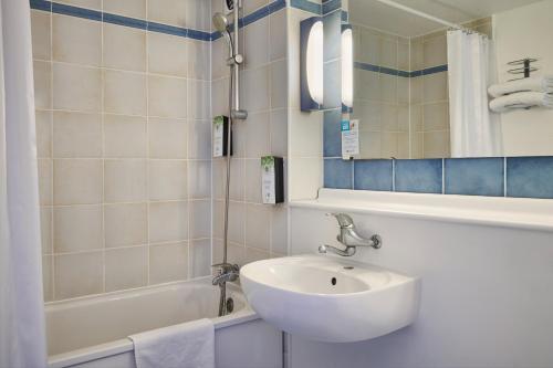La salle de bains est pourvue d'un lavabo, d'une baignoire et d'un miroir. dans l'établissement Kyriad Direct Haguenau, à Haguenau