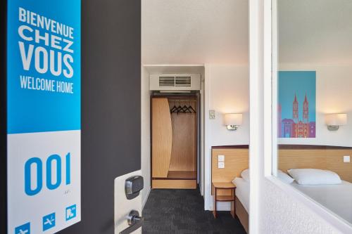 a hotel room with a bed and a hallway at Kyriad Direct Haguenau in Haguenau