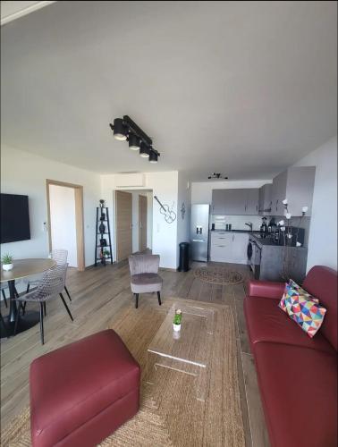 un salon avec un canapé rouge et une cuisine dans l'établissement Appartement dominant la baie d'Ajaccio, à Ajaccio